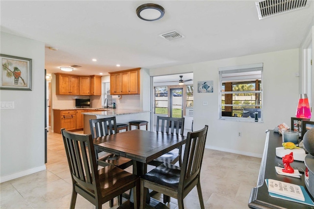 tiled dining room featuring ceiling fan and sink