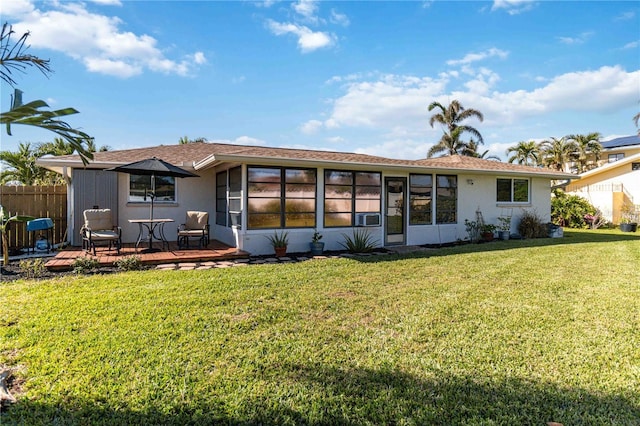 rear view of house featuring a sunroom, a lawn, and a wooden deck