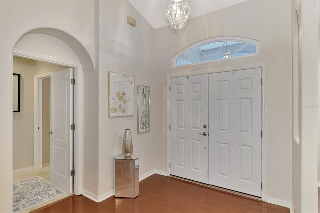 entrance foyer with dark hardwood / wood-style flooring, high vaulted ceiling, and a notable chandelier