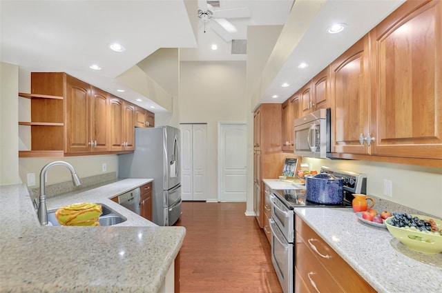 kitchen with light stone countertops, sink, dark wood-type flooring, and appliances with stainless steel finishes