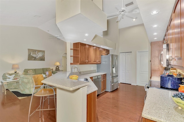 kitchen with sink, light wood-type flooring, appliances with stainless steel finishes, kitchen peninsula, and a breakfast bar area