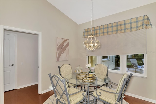 dining area with dark wood-type flooring, an inviting chandelier, and lofted ceiling