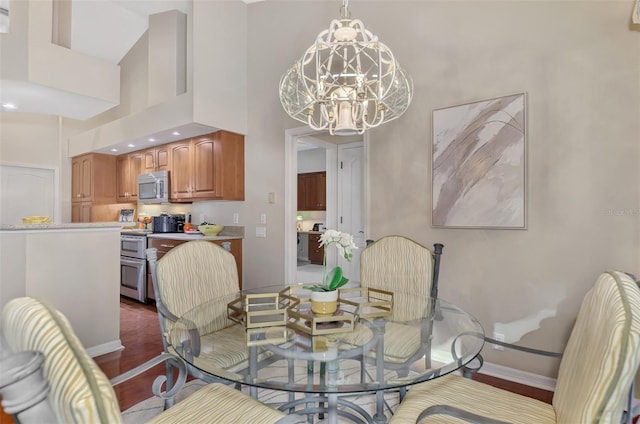 dining space with a towering ceiling, dark wood-type flooring, and a notable chandelier