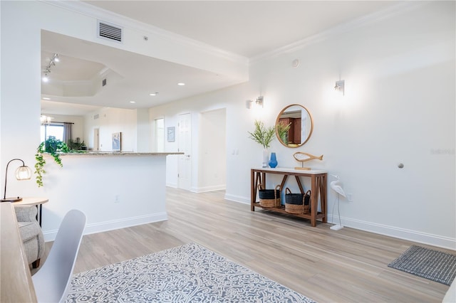 kitchen featuring kitchen peninsula, light stone counters, crown molding, a notable chandelier, and light hardwood / wood-style floors