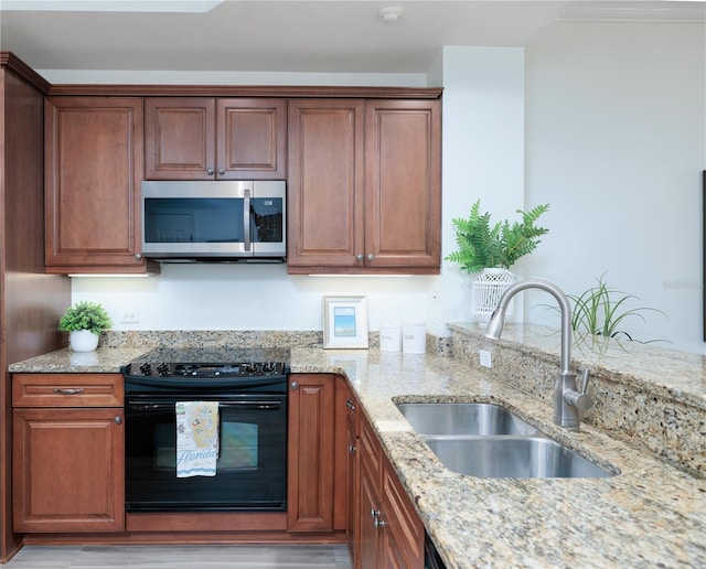 kitchen featuring light stone counters, black range, and sink