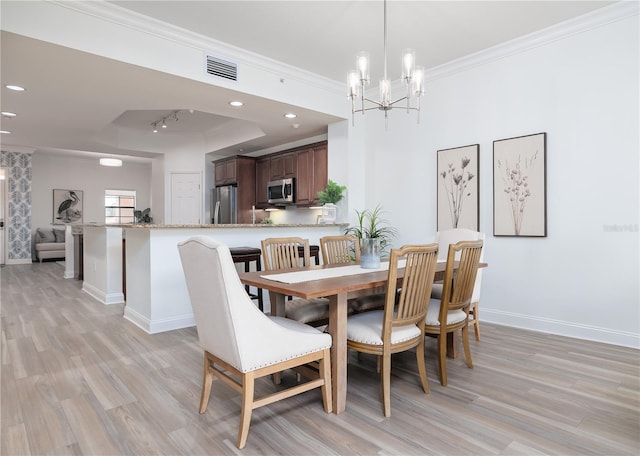 dining room with light wood-type flooring, an inviting chandelier, and ornamental molding