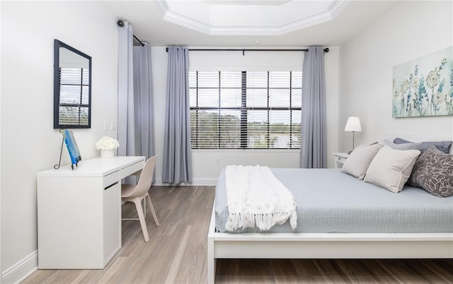 bedroom featuring a raised ceiling, wood-type flooring, and crown molding