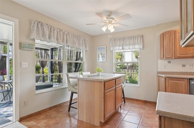 kitchen with a center island, ceiling fan, light tile patterned floors, tasteful backsplash, and a kitchen bar