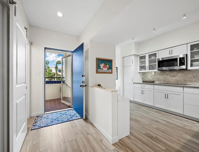 kitchen featuring decorative backsplash, white cabinetry, and light wood-type flooring