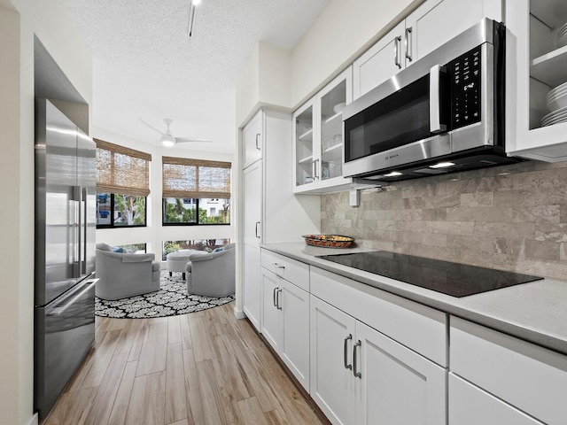 kitchen featuring light hardwood / wood-style floors, white cabinetry, appliances with stainless steel finishes, and tasteful backsplash