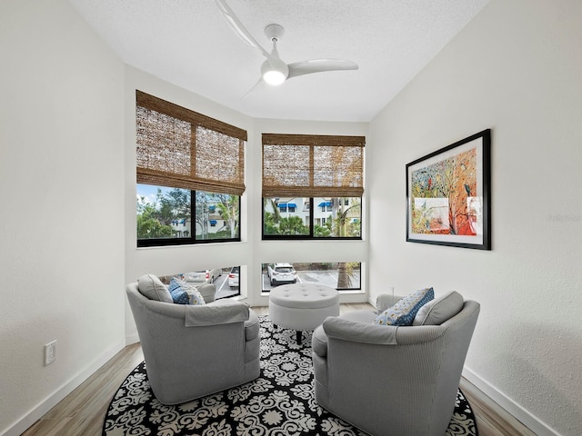 sitting room with ceiling fan, a textured ceiling, and hardwood / wood-style flooring