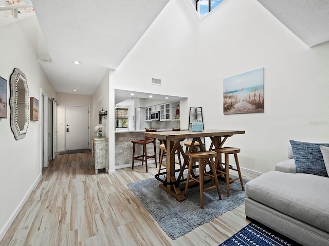 dining room featuring light hardwood / wood-style floors and a towering ceiling