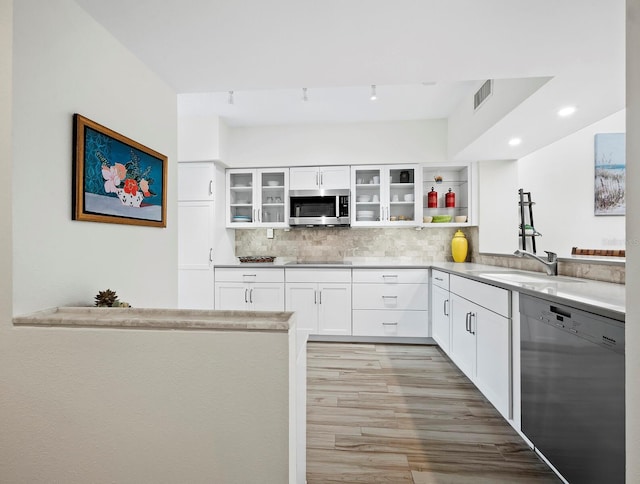 kitchen featuring kitchen peninsula, tasteful backsplash, dishwasher, white cabinets, and sink