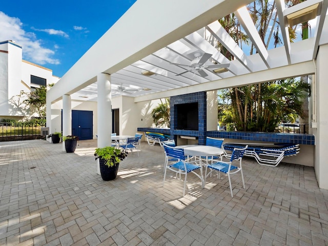 view of patio / terrace featuring ceiling fan, an outdoor fireplace, and a pergola