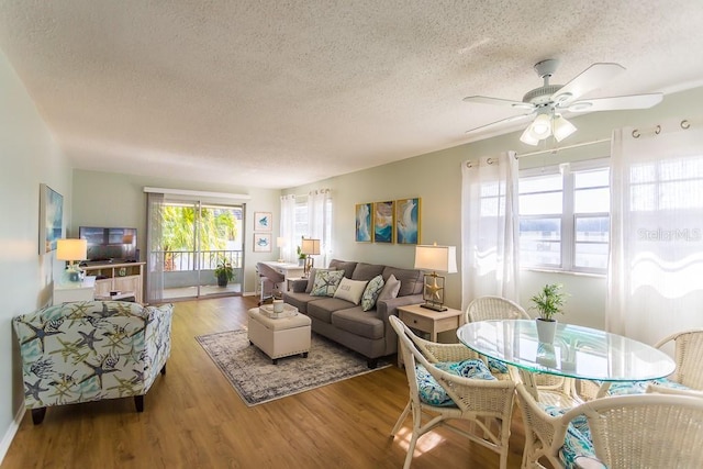 living room with ceiling fan, a textured ceiling, and light hardwood / wood-style flooring