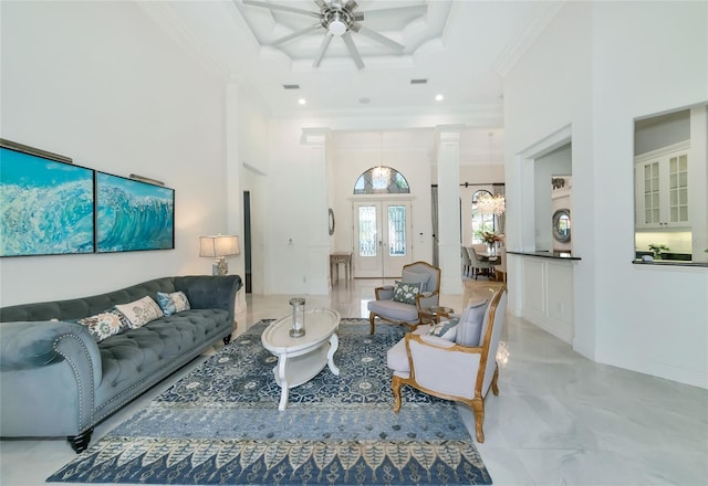 living room featuring french doors, ceiling fan with notable chandelier, ornamental molding, and a high ceiling