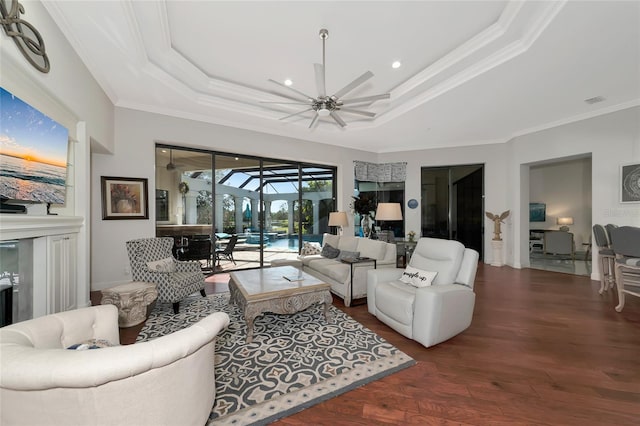 living room with dark hardwood / wood-style flooring, a raised ceiling, ceiling fan, and ornamental molding