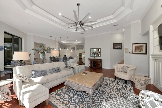 living room with dark hardwood / wood-style floors, ceiling fan, crown molding, and a tray ceiling