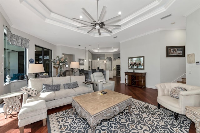 living room featuring dark hardwood / wood-style floors, crown molding, ceiling fan, and a tray ceiling