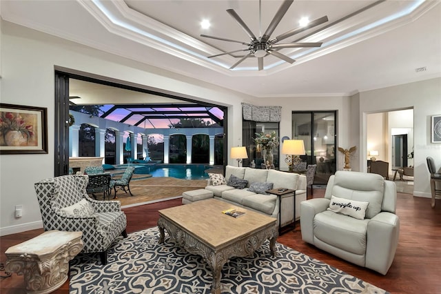 living room featuring a tray ceiling, crown molding, dark hardwood / wood-style flooring, and ceiling fan