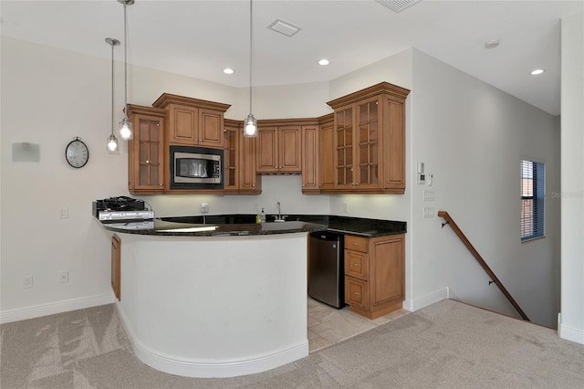 kitchen with light carpet, stainless steel appliances, and hanging light fixtures