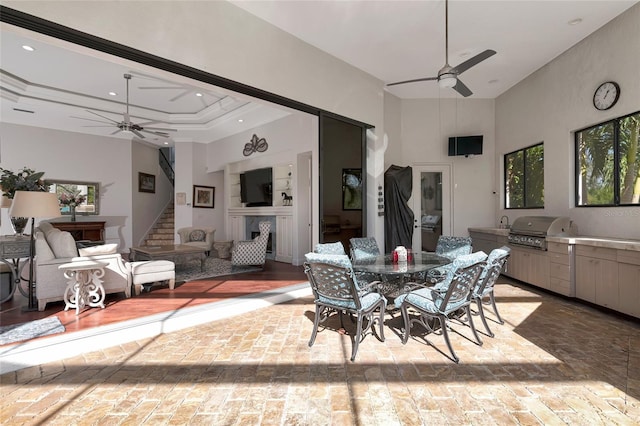 dining area with a fireplace, a high ceiling, ceiling fan, and ornamental molding