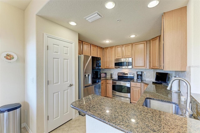 kitchen featuring tasteful backsplash, sink, appliances with stainless steel finishes, and dark stone counters