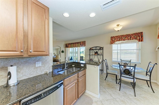 kitchen with sink, stainless steel dishwasher, a healthy amount of sunlight, and dark stone countertops