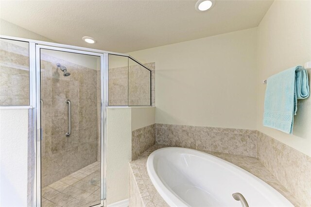 bathroom with a textured ceiling and independent shower and bath