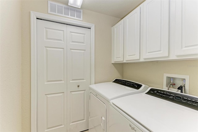 clothes washing area featuring cabinets and washing machine and dryer