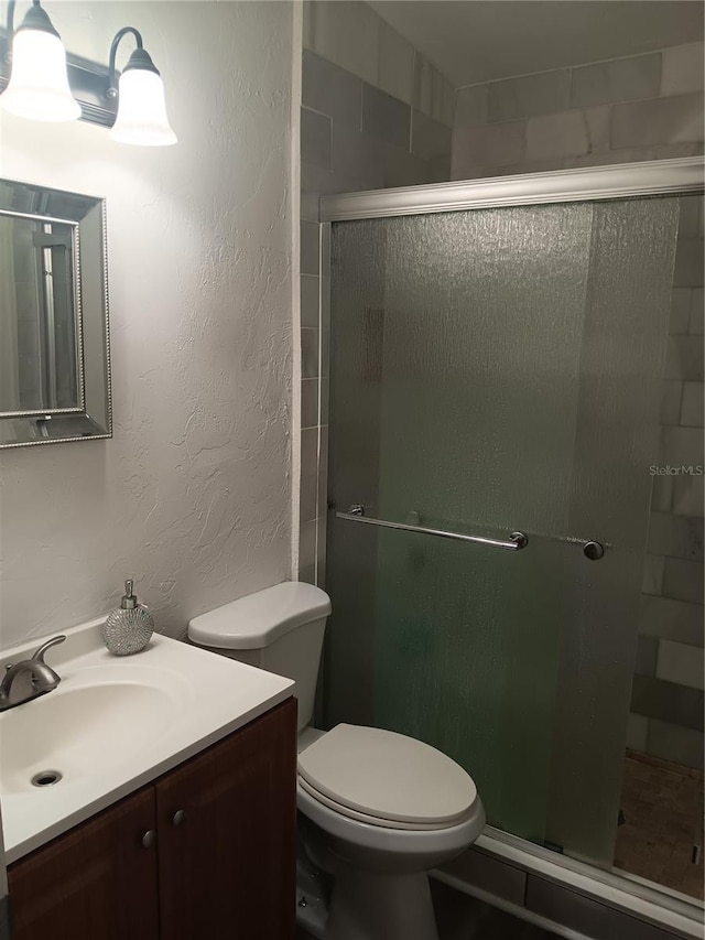 bathroom featuring vanity, toilet, and walk in shower