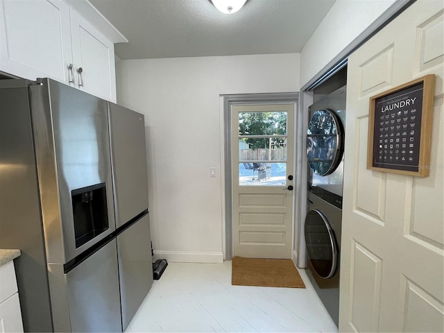 clothes washing area featuring stacked washer and dryer and a textured ceiling