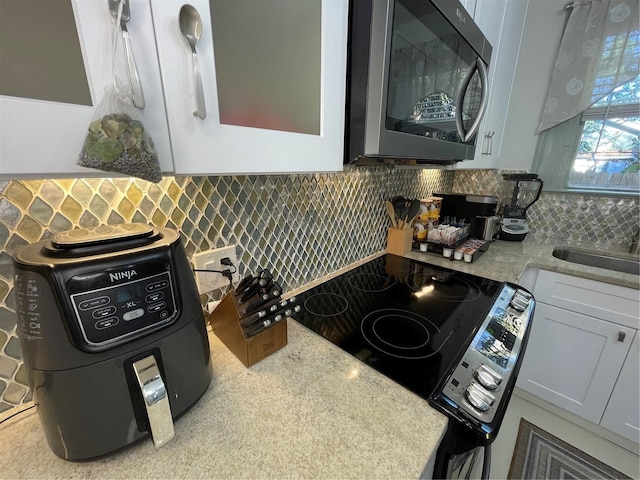 kitchen featuring decorative backsplash, light stone counters, white cabinetry, and sink