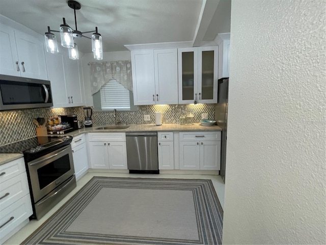 kitchen featuring white cabinets, stainless steel appliances, hanging light fixtures, and sink