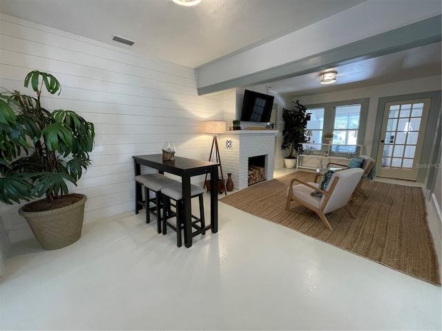 living room featuring concrete floors, a brick fireplace, and wood walls