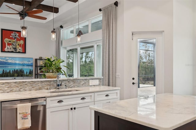 kitchen featuring tasteful backsplash, stainless steel dishwasher, sink, white cabinetry, and light stone countertops