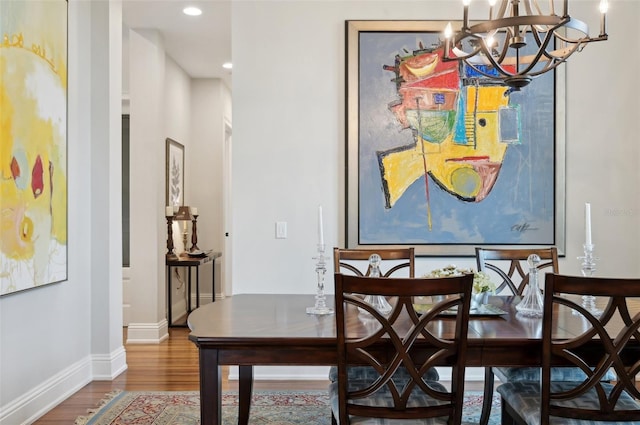 dining space with hardwood / wood-style floors and an inviting chandelier