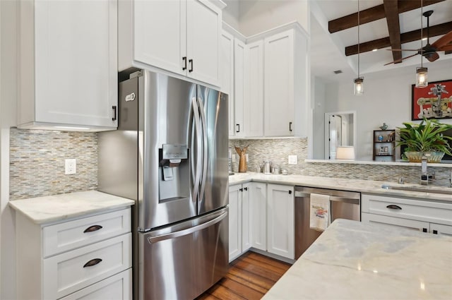 kitchen featuring stainless steel appliances, decorative backsplash, white cabinets, light stone counters, and beamed ceiling