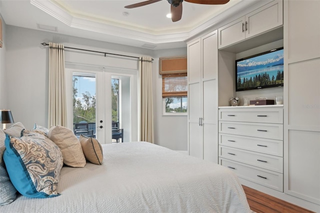 bedroom featuring dark hardwood / wood-style flooring, access to exterior, ceiling fan, a tray ceiling, and crown molding