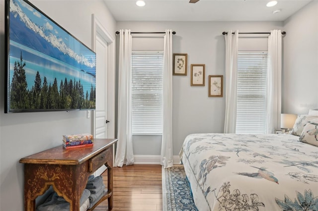 bedroom featuring ceiling fan, hardwood / wood-style flooring, and multiple windows