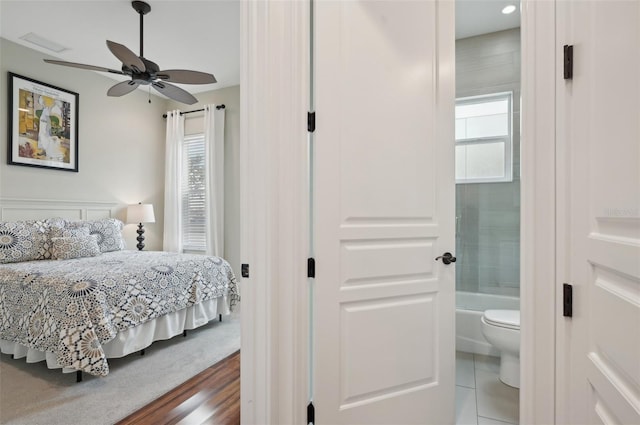 bedroom featuring ceiling fan, connected bathroom, and hardwood / wood-style flooring