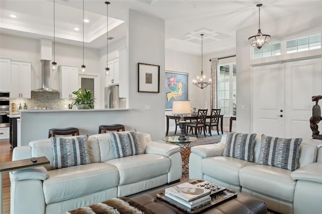 living room with hardwood / wood-style floors, a chandelier, ornamental molding, and a raised ceiling