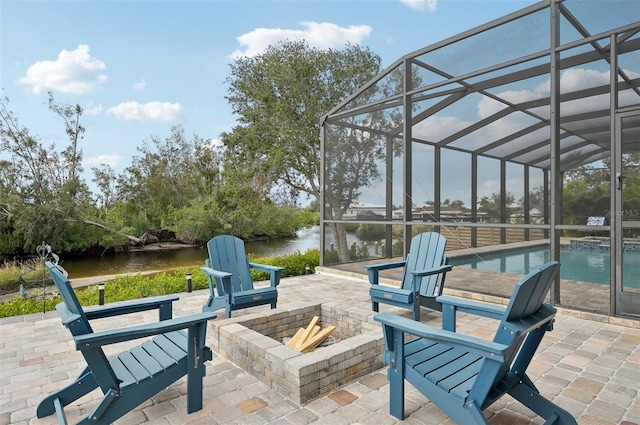 view of patio / terrace with a lanai, a fire pit, and a water view