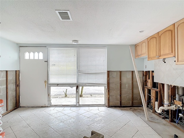 interior space with light brown cabinetry, a textured ceiling, and light tile patterned floors