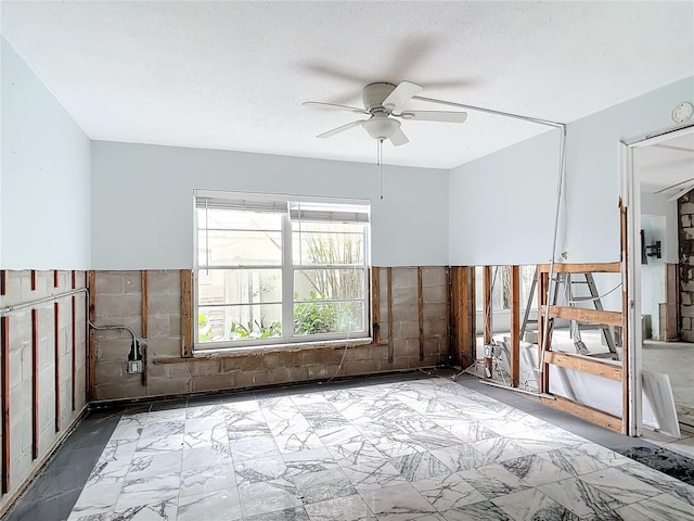 unfurnished room with tile walls, ceiling fan, and a textured ceiling