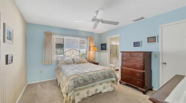 bedroom featuring a textured ceiling, ceiling fan, light carpet, and ensuite bath