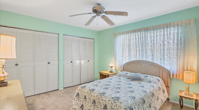 carpeted bedroom featuring ceiling fan and two closets