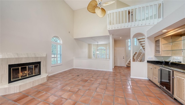 kitchen with light tile patterned flooring, a premium fireplace, beverage cooler, and a towering ceiling