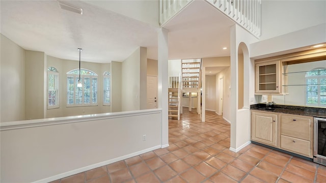 kitchen with light tile patterned floors, decorative light fixtures, beverage cooler, and light brown cabinetry