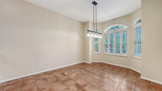 empty room featuring tile patterned floors, a textured ceiling, and a chandelier